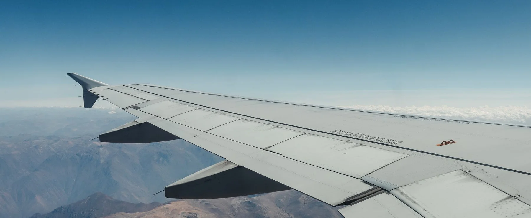 An aircraft wing above a mountain landscape, stock aviation photograph
